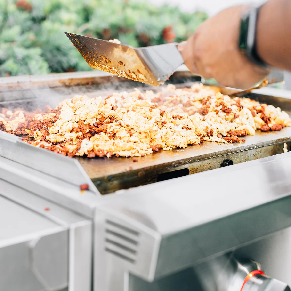 Breakfast of chorizo and eggs cooking on a Summerset GRID30 30-inch built-in gas griddle in an outdoor kitchen
