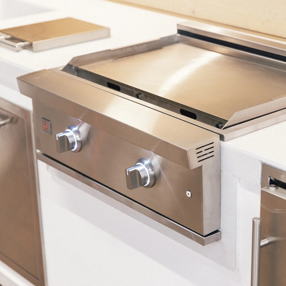 Summerset GRID30 30-inch gas griddle built into a white outdoor kitchen island with its stainless cover removed and set on the counter