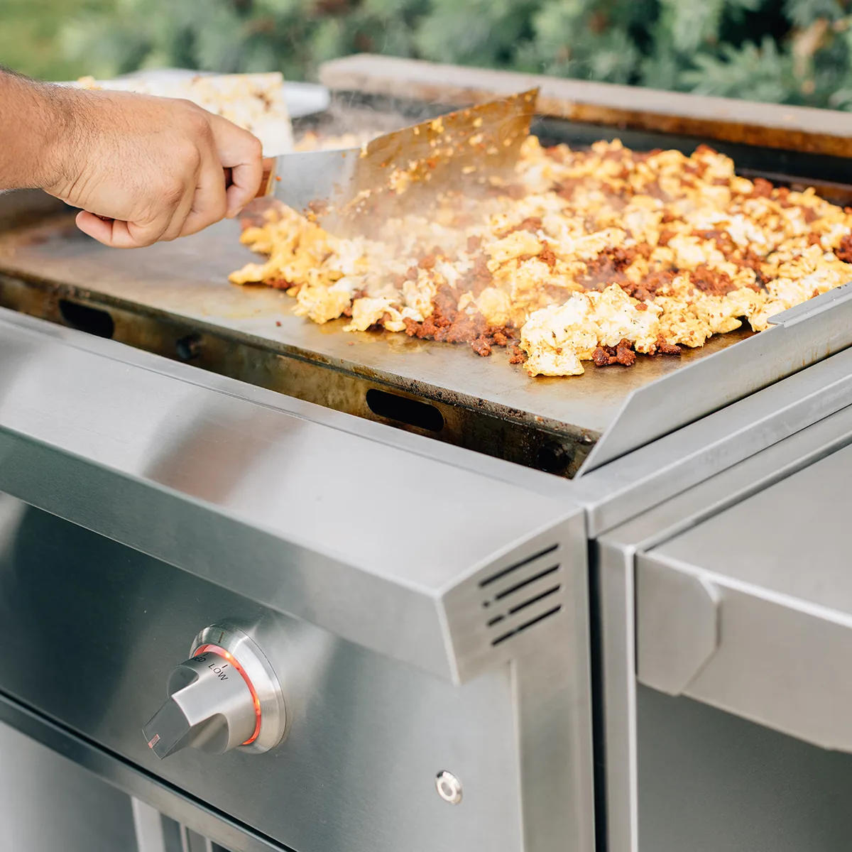 Cook using a steel spatula to turn chorizo and scrambled eggs on the flat top of a Summerset GRID30 30-inch gas griddle