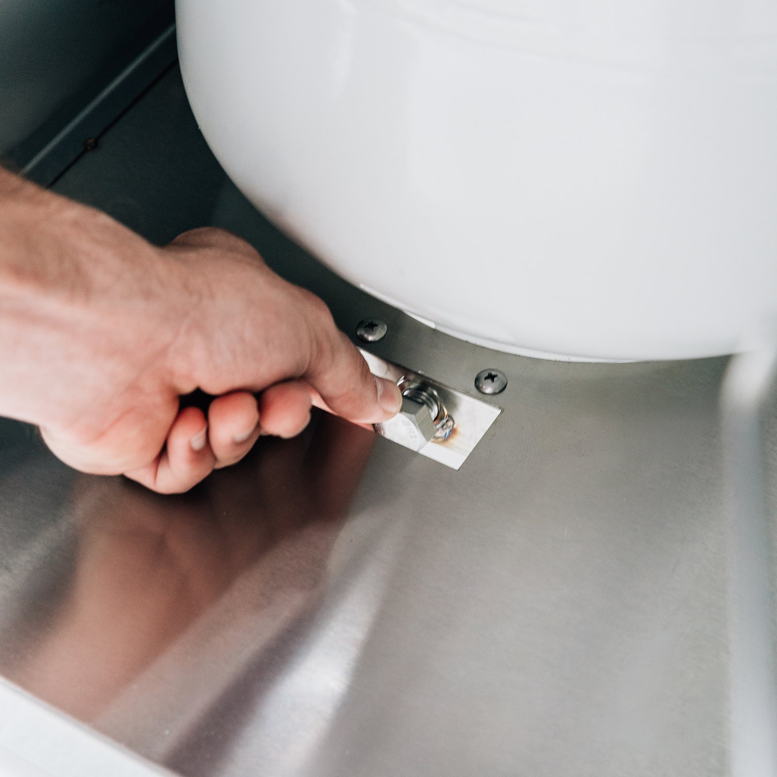 Hand securing the propane tank safety strap inside a Summerset grill cart's storage compartment