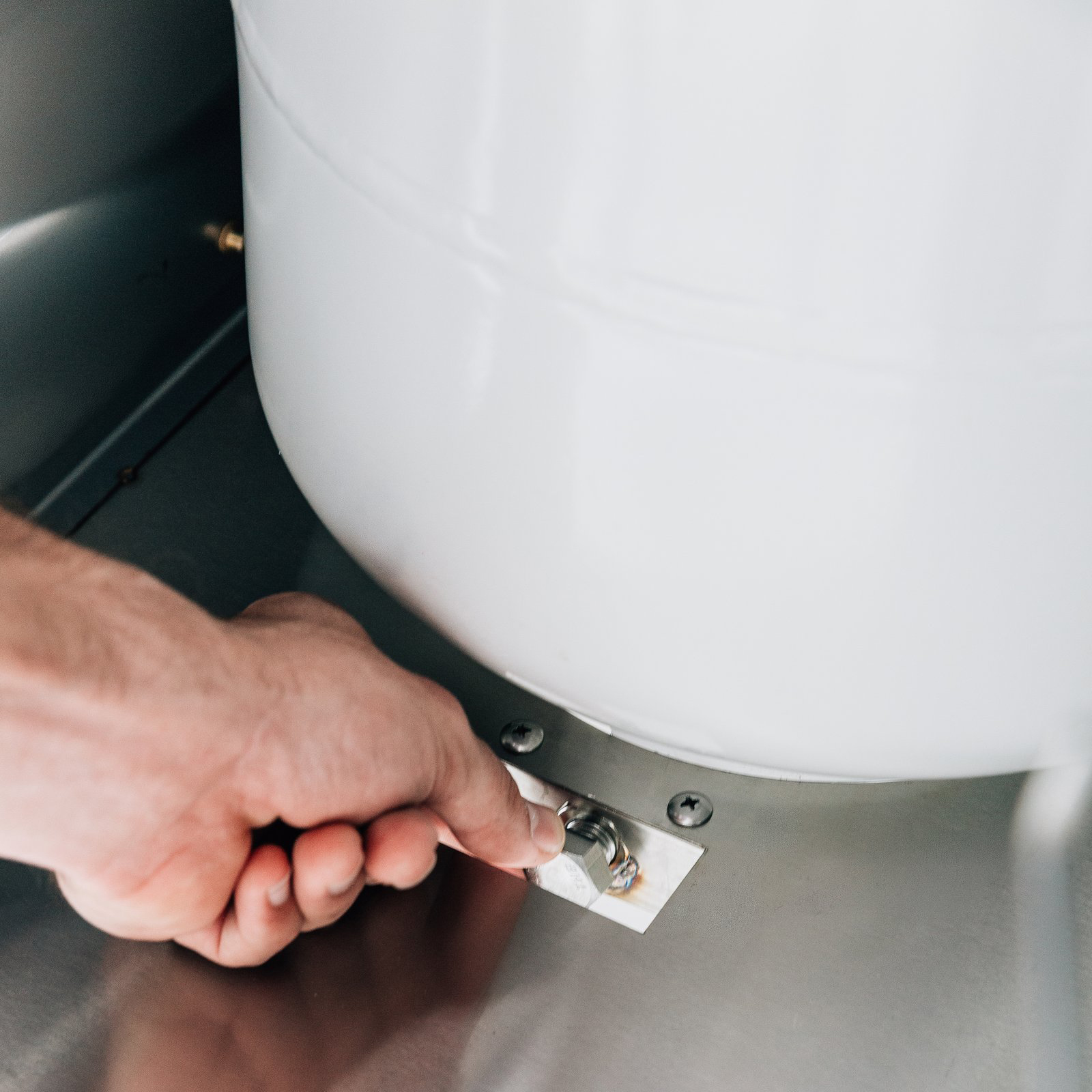 Hand securing the propane tank safety strap inside a Summerset grill cart's storage compartment