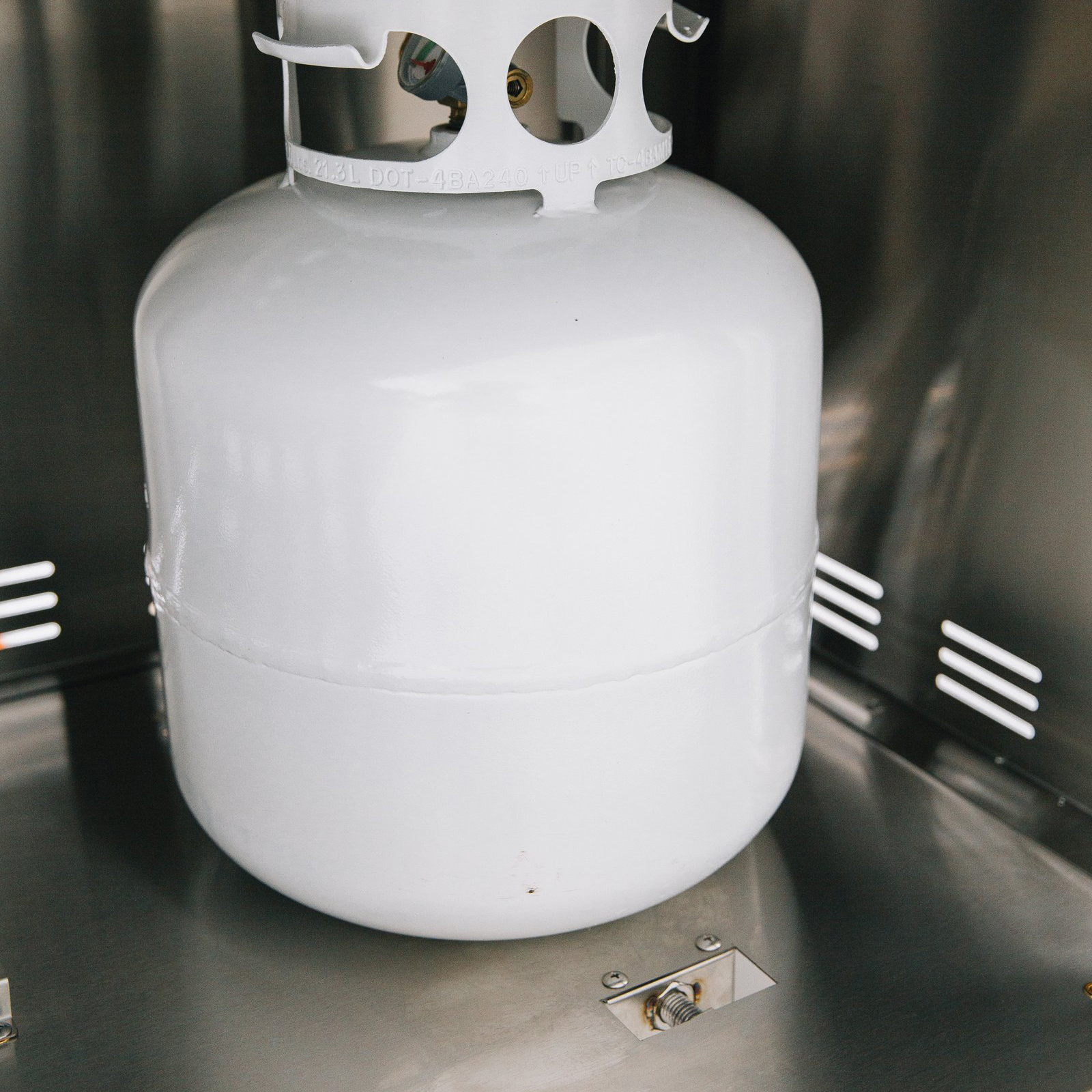 Propane tank secured inside the stainless steel storage compartment of a Summerset grill cart with double access doors