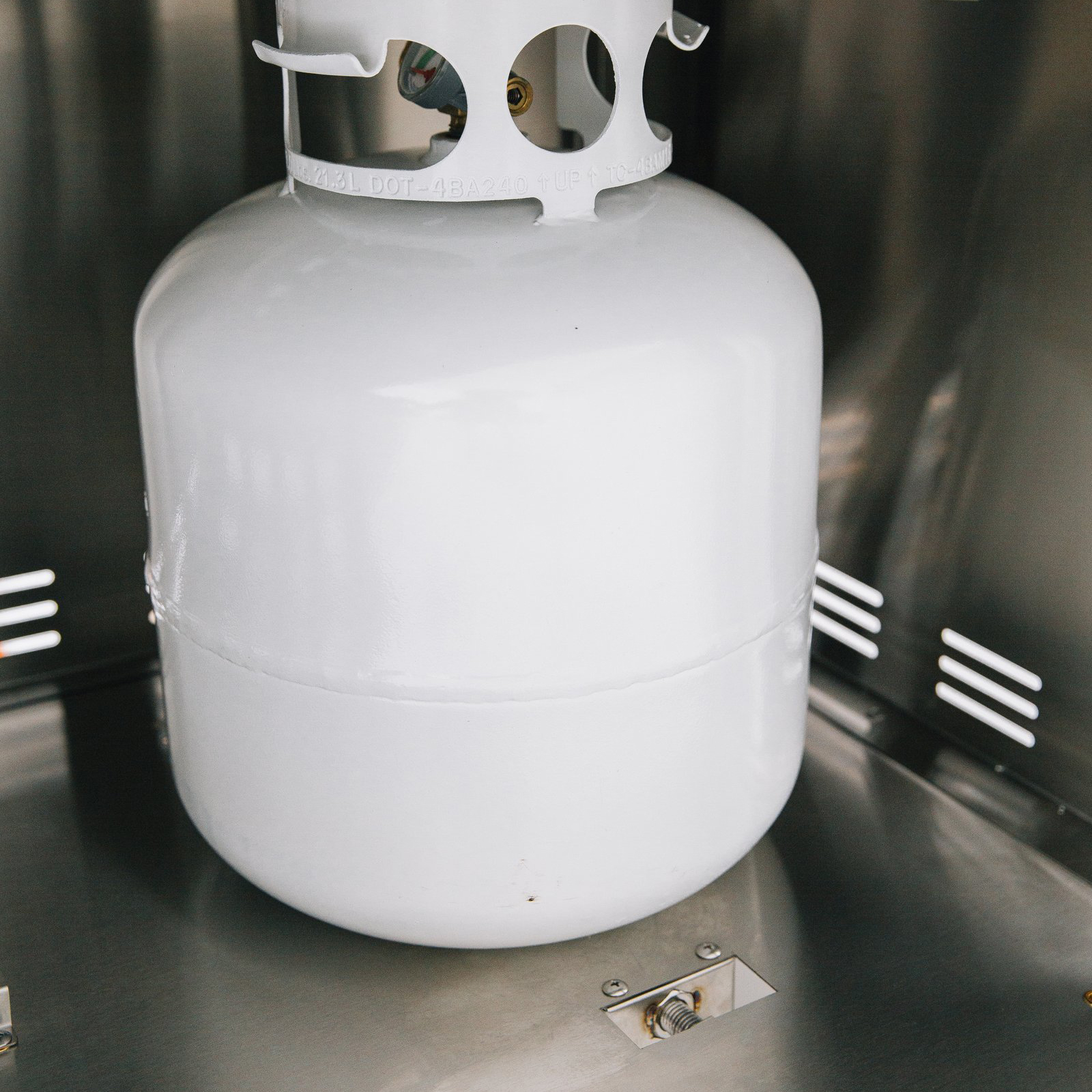 Propane tank secured inside the stainless steel storage compartment of a Summerset grill cart with double access doors