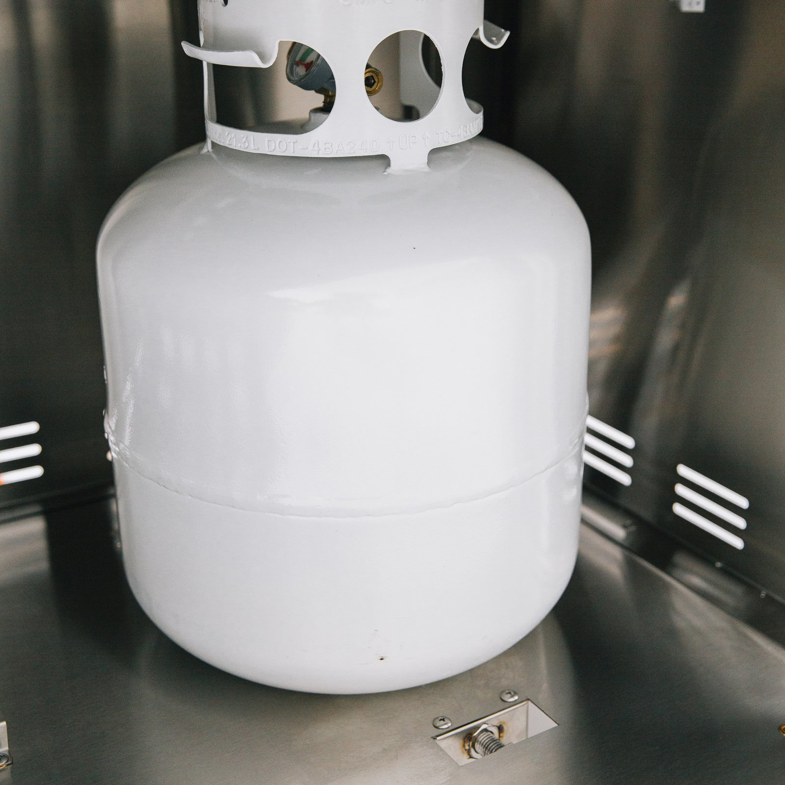 Propane tank secured inside the stainless steel storage compartment of a Summerset grill cart with double access doors